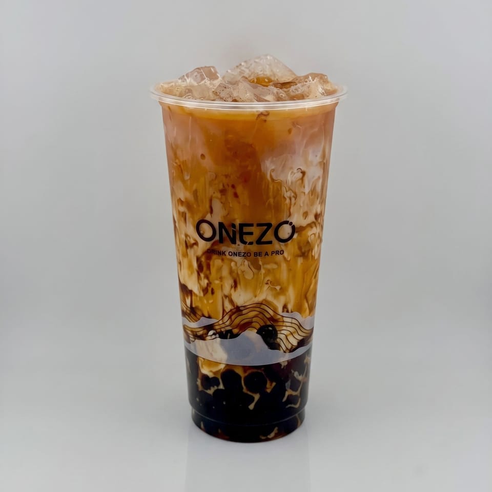 Iced milk tea with tapioca pearls in a clear Onezo cup, featuring caramel swirls and ice.